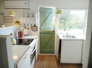 Eine Küche mit Herd, Spüle und einem Fenster mit Blick auf Bäume.