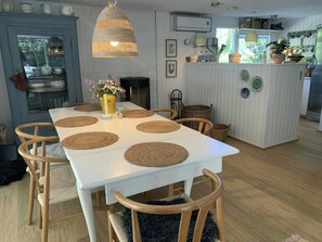 Ein Essbereich mit einem weißen Tisch, gewebten Platzsets und Holzkstühlen.