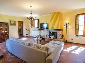 Ein Wohnzimmer mit Sofa, Fernseher, Kamin und einer Deckenleuchte.