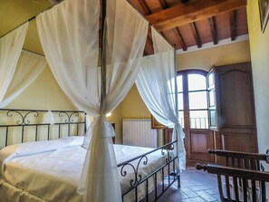 Ein Schlafzimmer mit Himmelbett, einer hölzernen Bank und einem Fenster mit Blick.