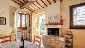 A dining area with a table set for two, a fireplace, and a window with curtains. - Historic village with pool near Todi (Todi)