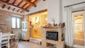 A rustic kitchen with a fireplace, wooden beams, and a dining area with a table and chairs. - Historic village with pool near Todi (Todi)