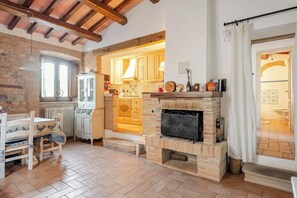 Eine rustikale Küche mit Kamin, Holzbalken und einem Essbereich mit Tisch und Stühlen.