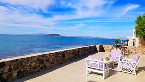 A seaside patio with stone walls, white wicker furniture, and a view of the sea and distant mountains. - 2 Story Cholla Bay Loft with Amazing Views and Private Beach Access Dog Friendly (Bahía la Choya)