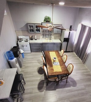 Une cuisine de taille réduite avec un coin repas, un ventilateur de plafond et un réfrigérateur.