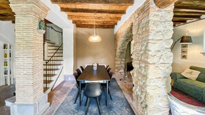 A dining area with a table and chairs, a staircase, and stone walls. - Farmhouse with pool amid ancient oaks in Tuscia (Viterbo)