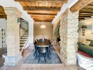 A dining area with a table and chairs, a staircase, and stone walls. - Farmhouse with pool amid ancient oaks in Tuscia (Viterbo)