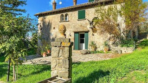 A stone building with a green door, a small window, and a stone staircase leading to the entrance. - Farmhouse with pool amid ancient oaks in Tuscia (Viterbo)