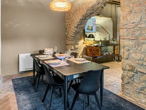 A dining area with a stone archway, a table set for four, and a mirror reflecting the room. - Farmhouse with pool amid ancient oaks in Tuscia (Viterbo)