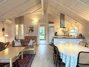 Ein gemütliches Interieur mit Essbereich, einer Couch mit Kissen, einer Küche mit Herd und Kühlschrank.