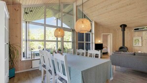 Et hyggeligt sommerhusinteriør med spiseområde, sofa og pejs.