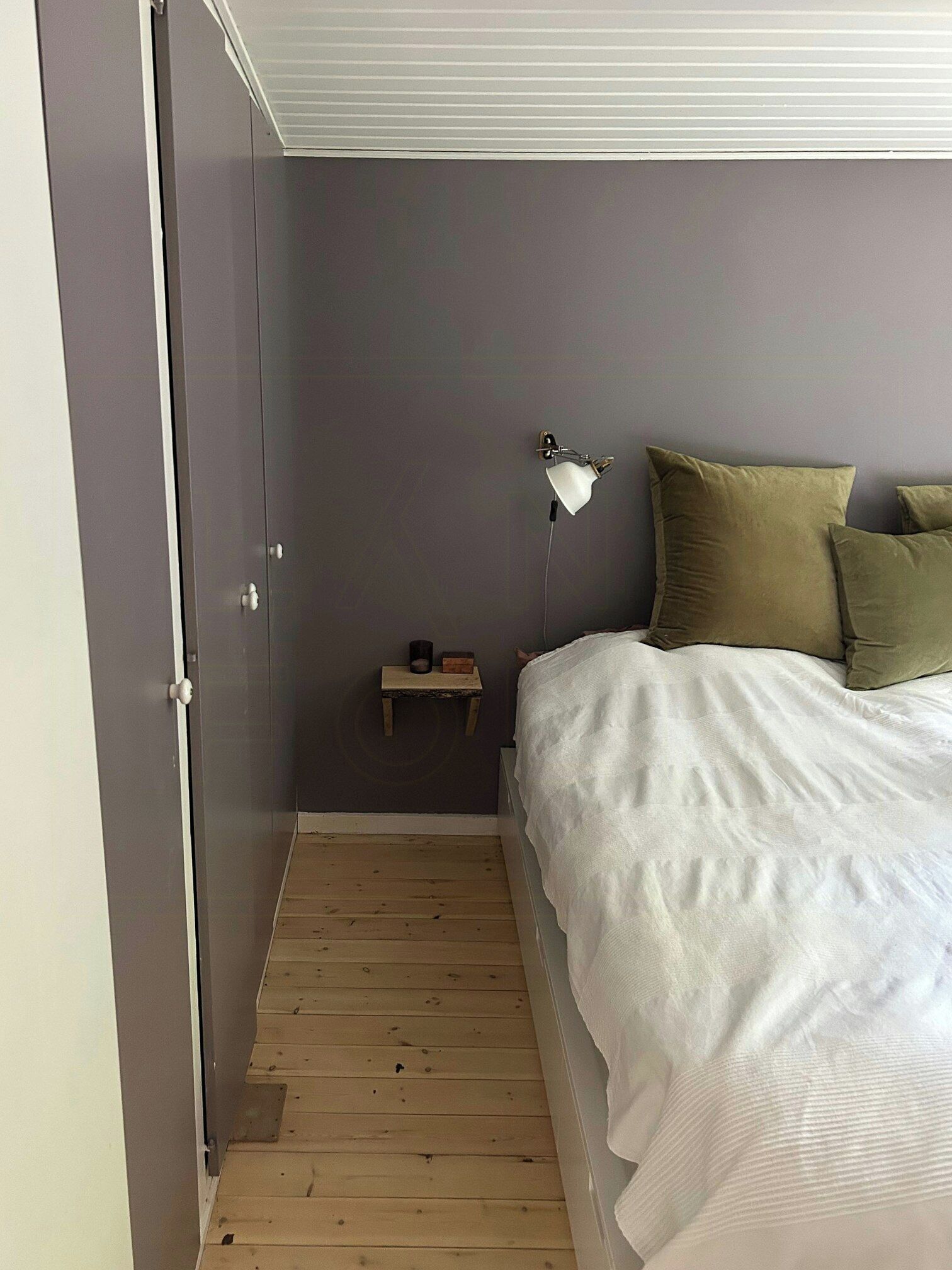 A bedroom with a bed, a nightstand, a lamp, and a door.