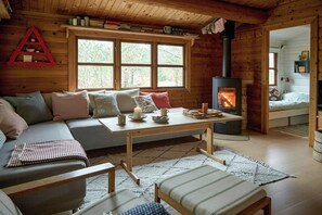 A cozy cabin interior with a wooden interior, a sofa, a table with candles, and a fireplace. - Cozy gem near Tversted Plantage (Aalbæk)