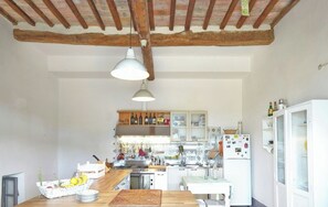 A kitchen with wooden beams, a hanging light fixture, a counter with a basket of fruit, and a refrigerator with magnets. - Rustic villa with pool in the heart of Chianti (San Casciano in Val di Pesa)