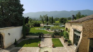 Un patio con un sendero de piedra, un estanque pequeño y vistas a montañas distantes.