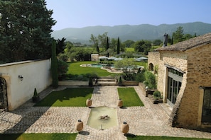 A courtyard with a stone pathway, a small pond, and a view of distant mountains. - 19th-century mas with pool and garden (Oppède)