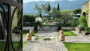 Un patio con una fuente, un sendero de piedra, mobiliario exterior y vistas a montañas.