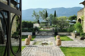 A courtyard with a fountain, stone pathway, outdoor seating, and a view of mountains. - 19th-century mas with pool and garden (Oppède)