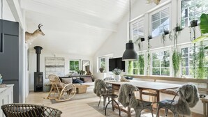 A spacious living area with a high ceiling, large windows, and a fireplace. - Step through the gate and feel peace in the woods (Silkeborg)