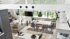 A modern kitchen with a dining area, wooden flooring, and a large window with a view of greenery. - Step through the gate and feel peace in the woods (Silkeborg)