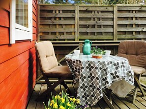 A patio with a table, two chairs, a potted plant, and a green kettle. - Cottage by the sea on Djurö (Djurhamn)