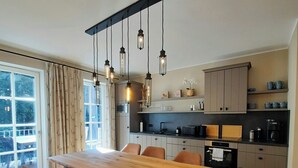 Una cucina moderna con un tavolo e sedie di legno, un forno a incasso e un'ampia finestra con tende.