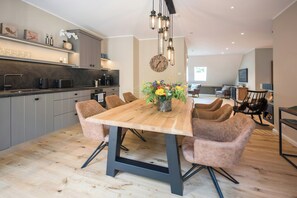 Eine moderne Küche mit einem Holztisch, Stühlen und einer Uhr an der Wand.