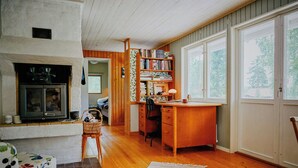 A cozy living room with a fireplace, a wooden desk, and a bookshelf. - Rustic cottage for creative souls by Lake Lingbo (Lingbo)
