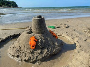 Ein sandiger Strand mit einem Sandkastenschloss, verziert mit einer Meeresschnecke.
