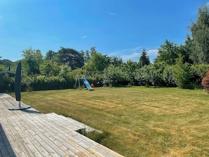 Ein Holzdeck, ein Rasen und eine Rutsche im Garten.