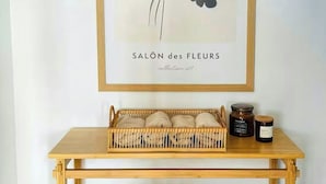 A framed botanical print titled 'SALON des FLEURS' above a wooden console table with woven baskets and jars. - Historic gatehouse at Søllestedgaard Manor (Søllested)