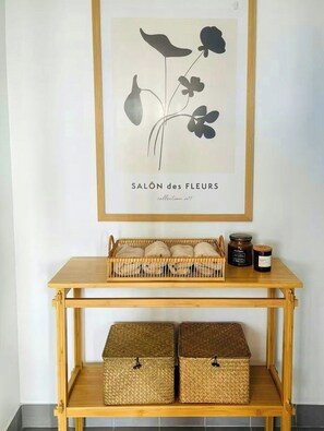 Un grabado botánico enmarco con el título 'SALON des FLEURS' sobre una consola de madera con cestas tejidas y frascos.