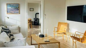 A modern living room with a sofa, coffee table, and chairs, a fireplace, and a TV. - Historic gatehouse at Søllestedgaard Manor (Søllested)