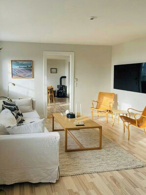 A modern living room with a sofa, coffee table, and chairs, a fireplace, and a TV. - Historic gatehouse at Søllestedgaard Manor (Søllested)