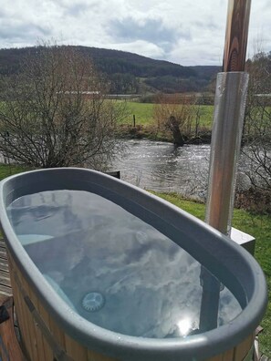 Ein Whirlpool mit freiem Blick auf einen Fluss und Hügel im Hintergrund.