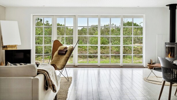 A spacious room with a large sliding glass door, a fireplace, a sofa, and a chair.