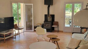 Una sala de estar con televisor, sofá, sillones, chimenea y un ventanal grande.