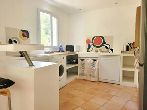 Eine Küche mit Waschmaschine, Mikrowelle und Spüle.