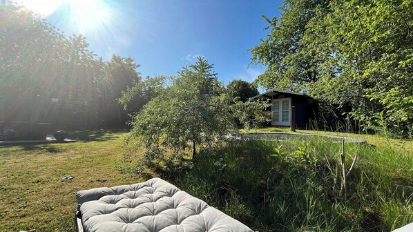 Ein kleines Haus mit Tür und Fenstern, umgeben von Bäumen und Gras.