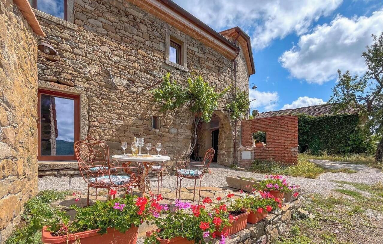 A stone building with a patio area featuring outdoor seating and potted plants.