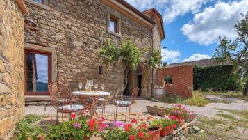 A stone building with a patio area featuring outdoor seating and potted plants.