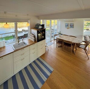 A modern kitchen with a dining area, large windows, and a view of the outdoors. - Holiday home by the water in Øer Maritime (Ebeltoft)
