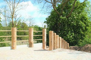 A wooden rope barrier, a paved walkway, and a large tree.