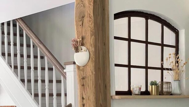 A staircase with white balusters, a wooden post, a window with a grid pattern, and a small table with a chair. - Idyllic Country House by the Castle Pond in Gorow (Satow)