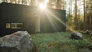A modern cabin with a large window, surrounded by rocks and forest. - Architect-designed cabin in Söderhamn archipelago (Söderhamn)