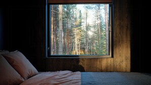 A bedroom with a large window, a bed, and a view of a forest. - Architect-designed cabin in Söderhamn archipelago (Söderhamn)