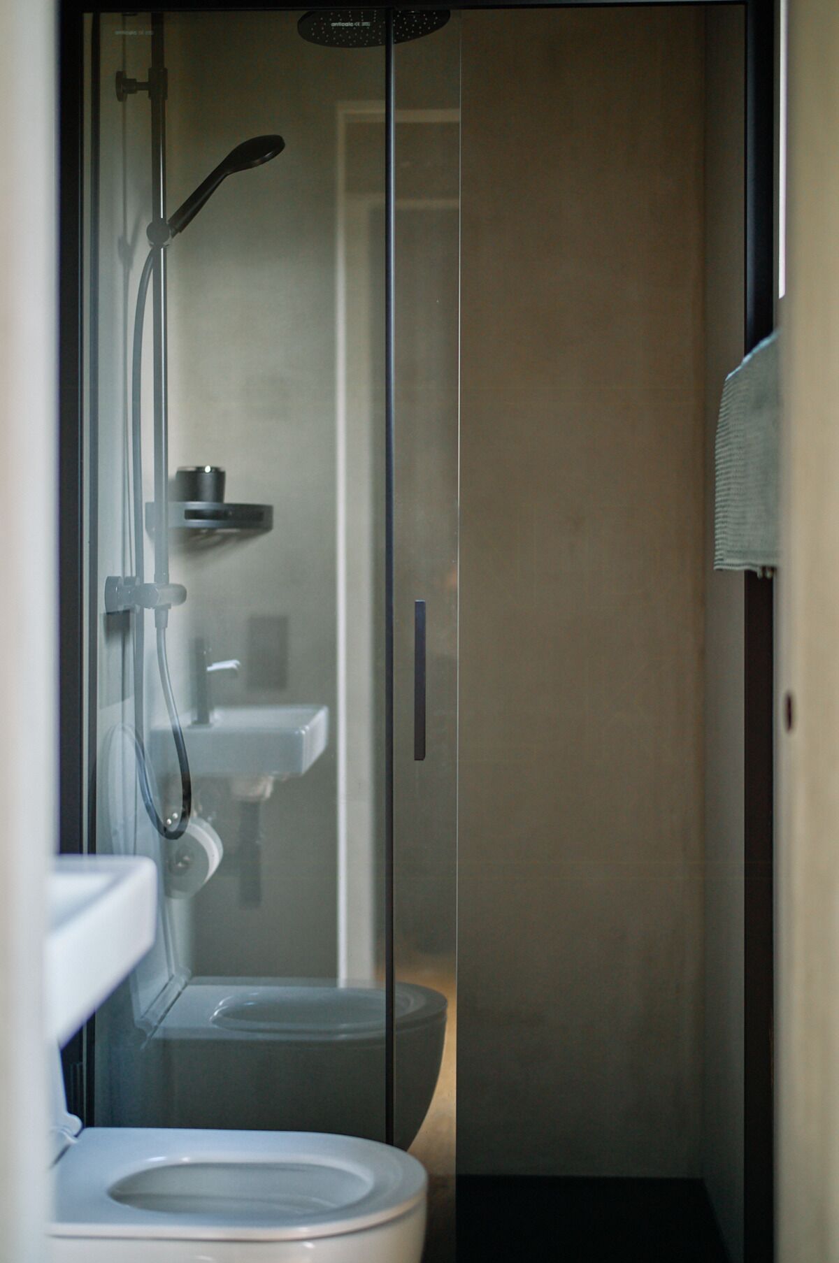 Ein kleines Badezimmer mit Duschkabine aus Glas, Toilette und Waschbecken.