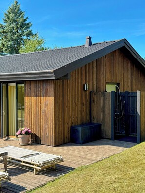A modern wooden building with a sloped roof, a wooden deck, and a potted plant. - Holiday home on nature plot near Vejby Strand (Vejby)