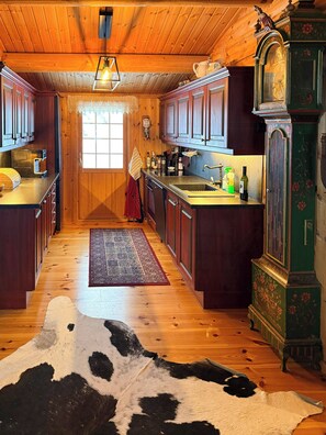 A wooden interior with a kitchen, a cowhide rug, and a clock. - Mountain cabin by Femunden facing Sølen (Engerdal)