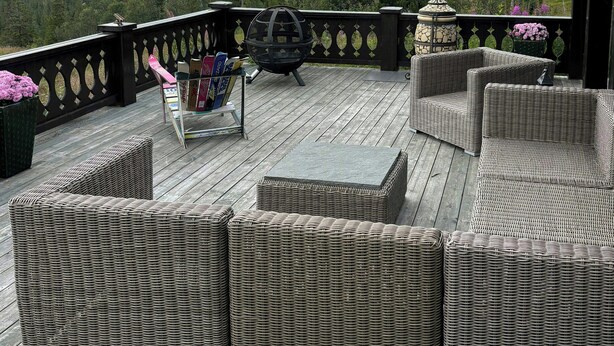 A deck with wicker furniture, a telescope, and a view of mountains.